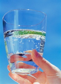 Hand holding glass of sparkling water with lime slice